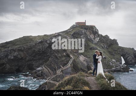 Bridal couple on bridge, Gaztelugatxe, Spain Stock Photo