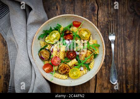 Bowl of pasta salad with grilled zucchini, tomatoes, arugula, Spanish onion and balsamic vinegar Stock Photo