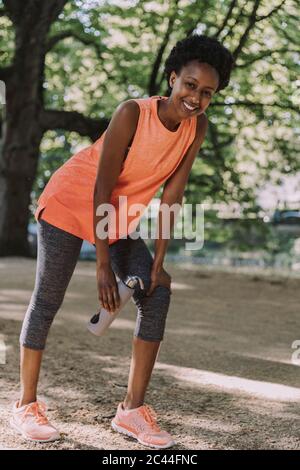 Portrait of smiling young woman taking a break from working out in a park Stock Photo