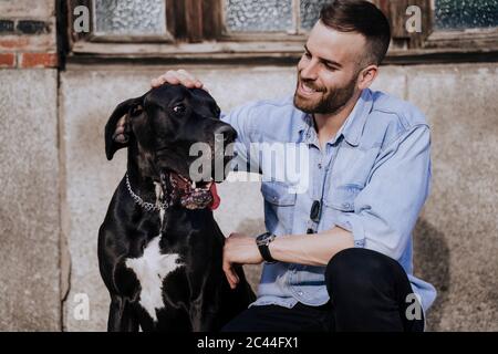 Smiling man stroking his dog outdoors Stock Photo