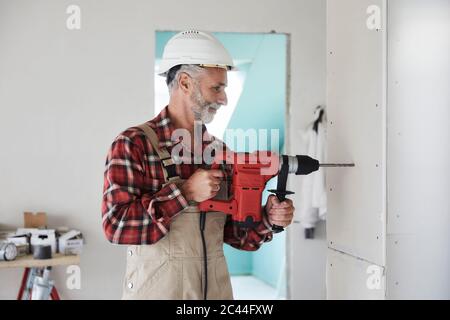 Construction worker drilling at construction site Stock Photo