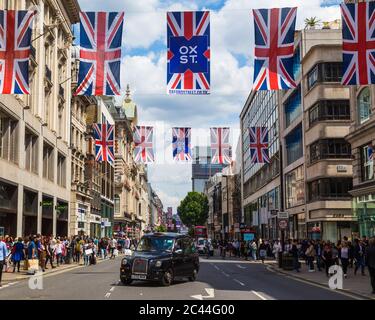 LONDON, UK - 28TH JUNE 2016: A view along Oxford Street in London during the day. A black London taxi, union jack flags and lots of people can be seen Stock Photo