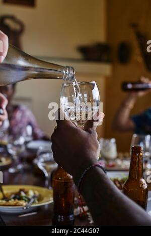 Cropped hand of man pouring water for friend at dining table Stock Photo