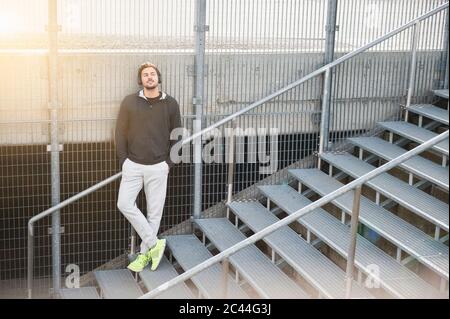 Sporty young man listening to music on stairs Stock Photo