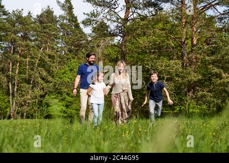 Family on grass against trees during sunny day Stock Photo