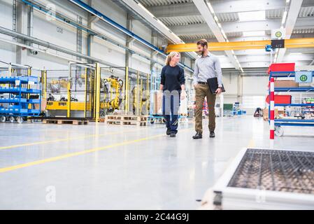 Man and a woman walking and talking in a factory