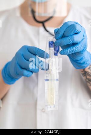 Woman in protective wear putting medical test into a bag Stock Photo