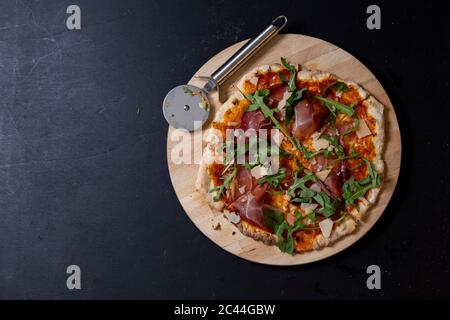 Studio shot of homemade pizza with Mozzarella, ham, arugula and Parmesan Stock Photo