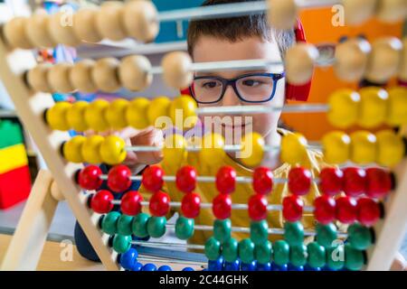 Boy calculating with colorful abacus at home Stock Photo