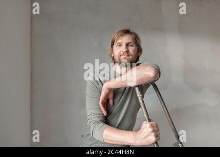 Confident man leaning on ladder during renovation Stock Photo