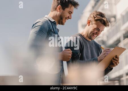 Colleagues brainstorming on balcony, writing down their ideas Stock Photo