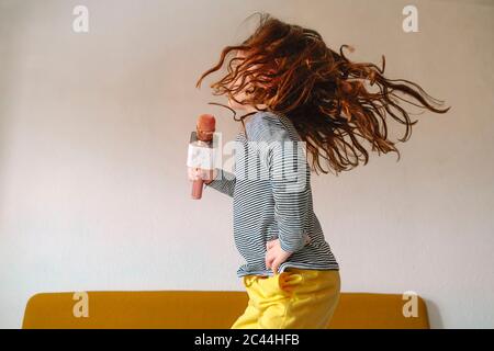 Girl jumping on bed and singing in micro Stock Photo