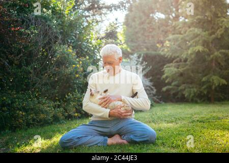 Senior man cuddling with his cat in garden Stock Photo