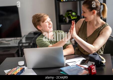 Mother homeschooling her son and using laptop at home Stock Photo