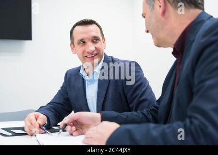 Two businessmen talking at desk in office Stock Photo