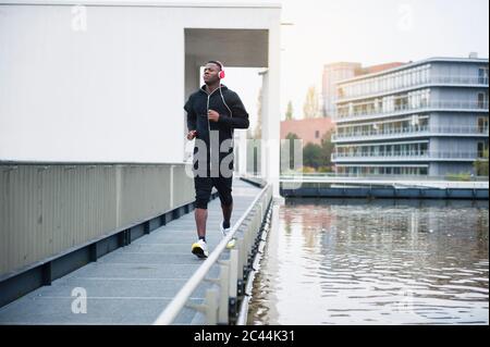 Young man with headphones jogging in the city Stock Photo