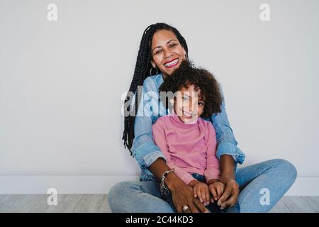 Portrait of happy mother and her little daughter sitting together on the floor Stock Photo