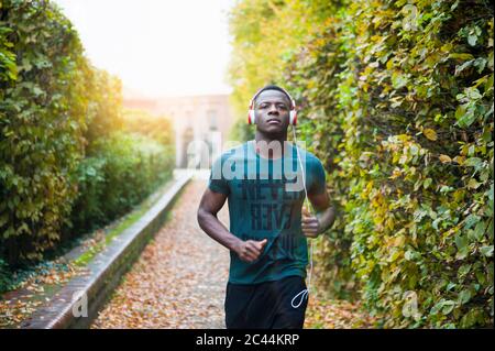 Young man with headphones jogging in park Stock Photo