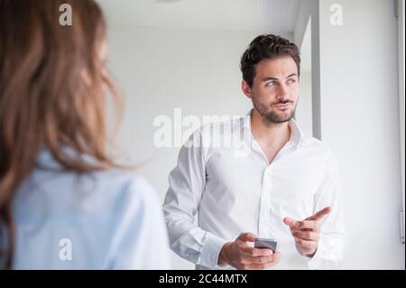Confident businessman pointing while discussing with female colleague in office Stock Photo