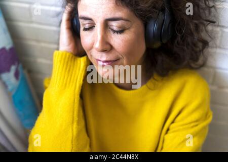 Portrait of woman with closed eyes listening to music with headphones