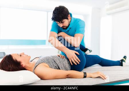 Male visually impaired physical therapist treating woman's leg in clinic Stock Photo