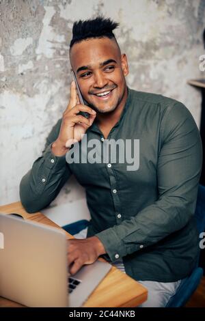 Portrait of smiling young man on the phone working at home office Stock Photo