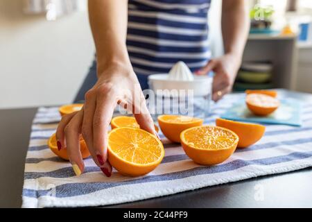Womanpreparing fresh orange juice, taking sliced orange Stock Photo