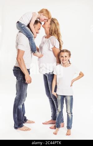 Pregnant woman with husband and two children standing in front of white background Stock Photo