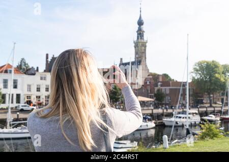 Netherlands, Zeeland, Veere, woman taking photo of old town Stock Photo