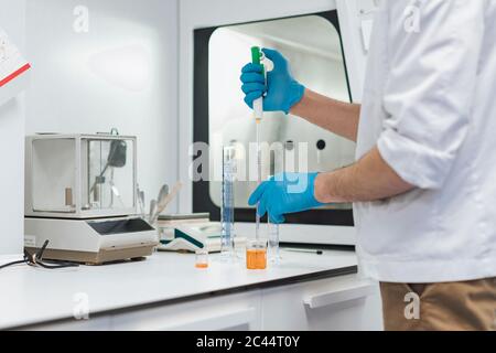 Young male technician using pipette at laboratory Stock Photo
