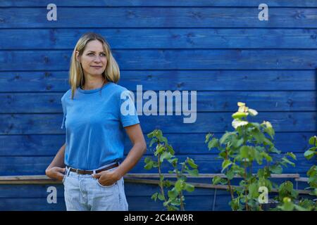 Portrait of woman standing at blue garden shed Stock Photo