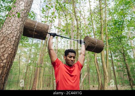 Sportsman exercising with wooden barbells in the forest Stock Photo