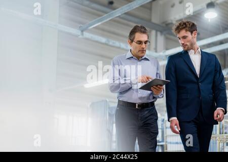Two businessmen with tablet having a meeting in a laundry shop Stock Photo