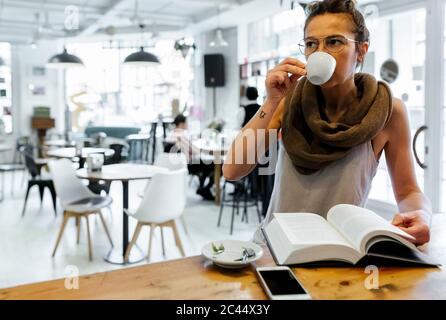 Woman reading book in coffee shop drinking coffee Stock Photo