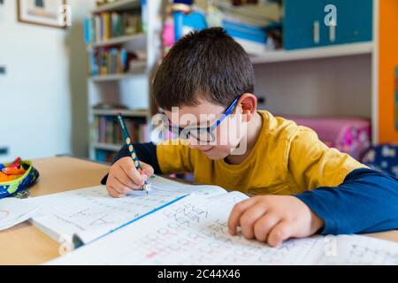 Elementary student learning while sitting at desk during homeschooling Stock Photo