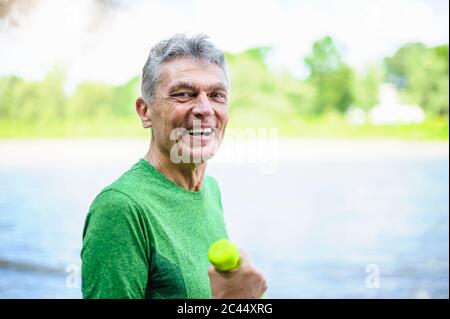 Side view portrait of smiling active senior man exercising in park Stock Photo