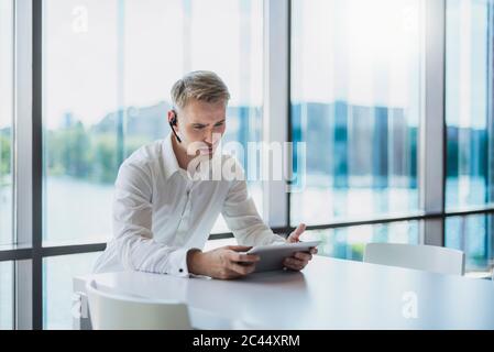 Businessman doing a call with a headset, using digital tablet Stock Photo