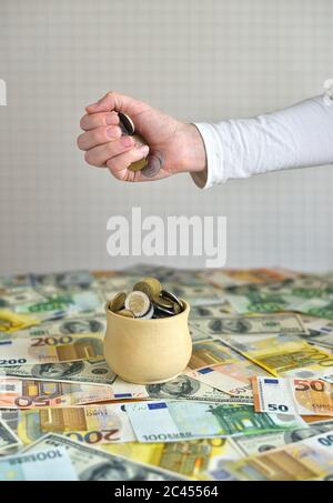 coins are falling in the cup. coins pour out of a female hand Stock Photo
