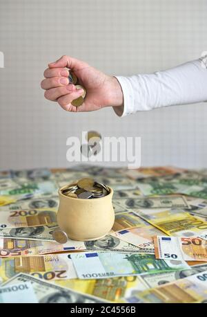 coins are falling in the cup. coins pour out of a female hand Stock Photo
