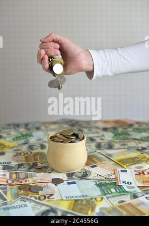 coins are falling in the cup. coins pour out of a female hand Stock Photo