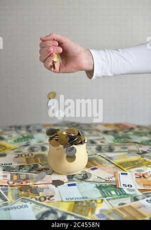 coins are falling in the cup. coins pour out of a female hand Stock Photo