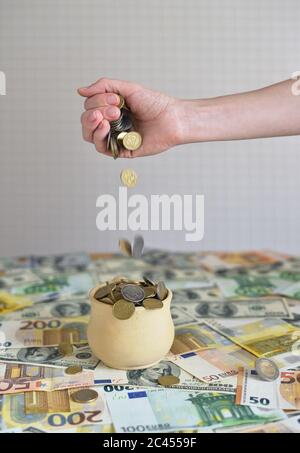 coins are falling in the cup. coins pour out of a female hand Stock Photo