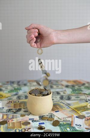 coins are falling in the cup. coins pour out of a female hand Stock Photo