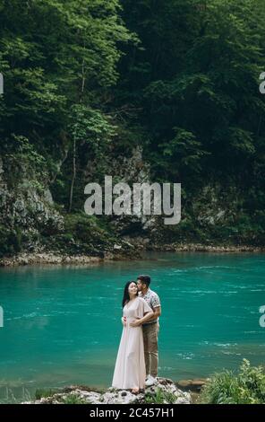 Young couple in the nature. A man hugs a woman on a background of a beautiful view of the river. Stock Photo