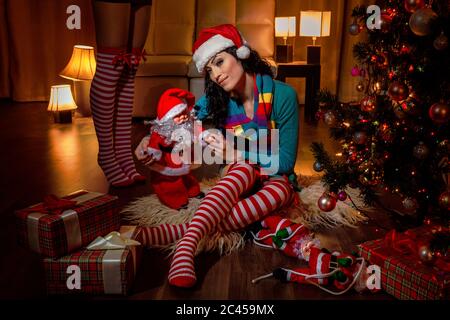 Smiling woman in Santa hat with Santa Claus toy and gift boxes Stock Photo