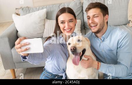 Young couple taking selfportrait with dog at home Stock Photo
