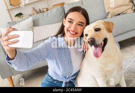 Young woman with her dog taking selfportrait at home Stock Photo