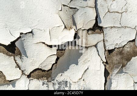Old cracked plaster white wall background. Textured surface of the exterior wall of building. Repair and restoration concept. Outdoors Stock Photo