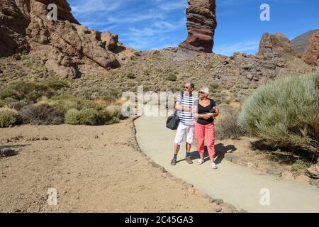 Aged couple are posing on trail near Garcia Rocks with Cinchado rock on background in Teide National Park, Tenerife, Canary Islands, Spain. Stock Photo