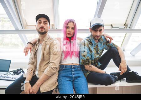 Portrait of young woman with long pink hair and two bearded young men wearing baseball caps. Stock Photo
